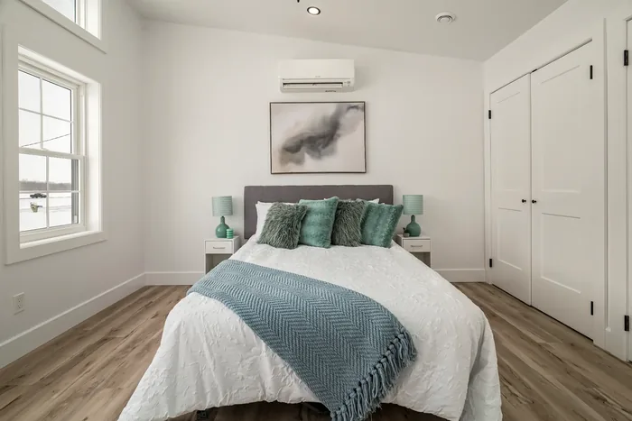 The master bedroom of a finished REDI-HOME, with a wall-mounted mini-split above the bed and a double closet alongside.